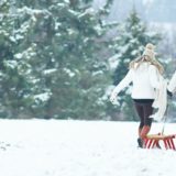 Couple pulling a sled together in snowy winter landscape